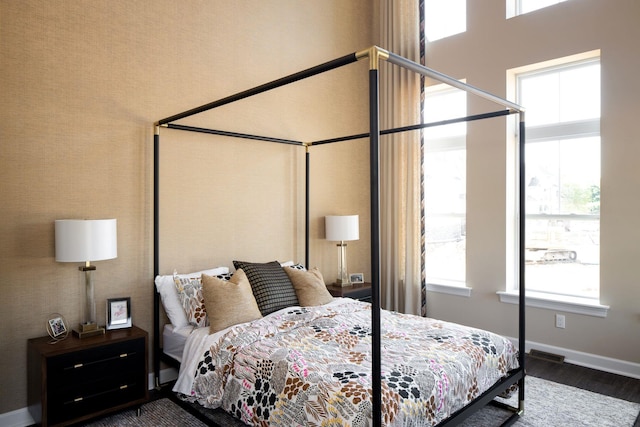 bedroom featuring baseboards, multiple windows, wood finished floors, and visible vents