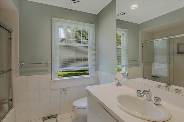 bathroom with toilet, tile walls, visible vents, and a wainscoted wall