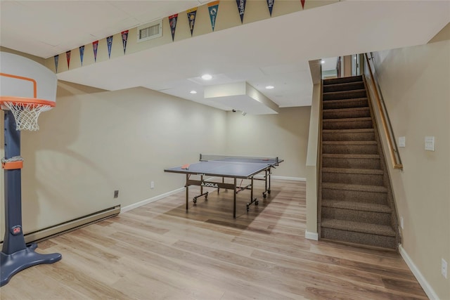 playroom with baseboards, a baseboard radiator, wood finished floors, and visible vents