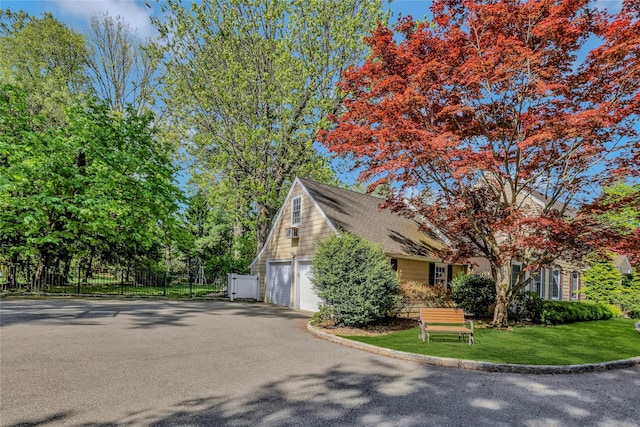 view of side of property featuring a lawn, fence, driveway, and a garage