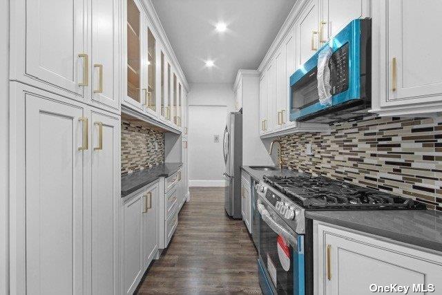 34-24 82nd St Unit 6E, Jackson Heights, NY 11372 - kitchen with appliances with stainless steel finishes, dark countertops, white cabinetry, backsplash, and glass insert cabinets