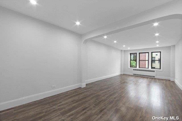 34-24 82nd St Unit 6E, Jackson Heights, NY 11372 - spare room featuring radiator heating unit, recessed lighting, baseboards, and dark wood-style floors