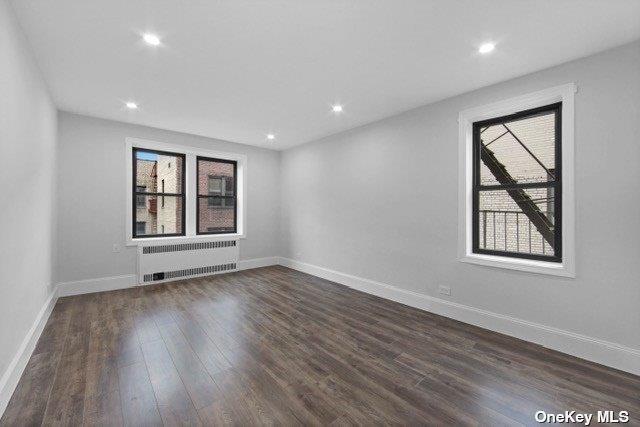 34-24 82nd St Unit 6E, Jackson Heights, NY 11372 - empty room featuring radiator, dark wood-style floors, baseboards, and recessed lighting