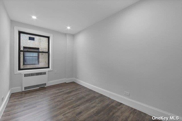 34-24 82nd St Unit 6E, Jackson Heights, NY 11372 - empty room with radiator heating unit, baseboards, dark wood-style floors, and recessed lighting