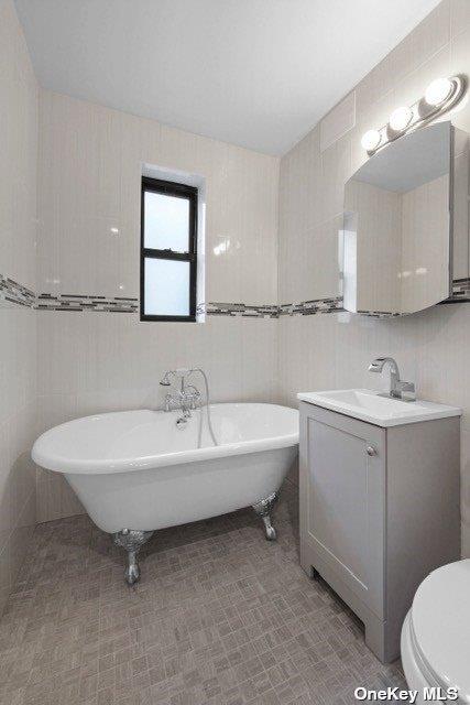 34-24 82nd St Unit 6E, Jackson Heights, NY 11372 - bathroom with tile walls, a soaking tub, vanity, and toilet