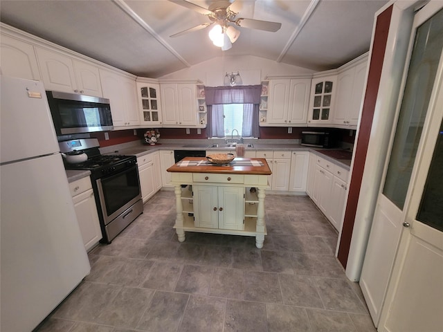 kitchen featuring a ceiling fan, appliances with stainless steel finishes, a center island, open shelves, and lofted ceiling