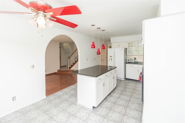 57 E Rock Cut Rd, Walden, NY 12586 - kitchen featuring dark countertops, arched walkways, white refrigerator with ice dispenser, a ceiling fan, and glass insert cabinets