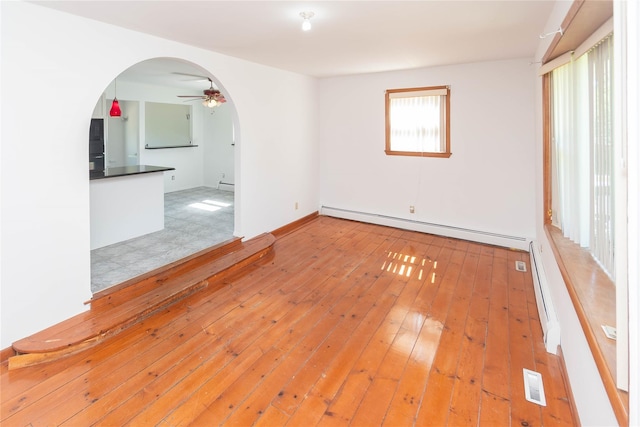 57 E Rock Cut Rd, Walden, NY 12586 - unfurnished room featuring a baseboard heating unit, arched walkways, a ceiling fan, light wood finished floors, and a baseboard radiator