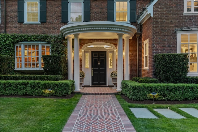 property entrance featuring brick siding and a lawn