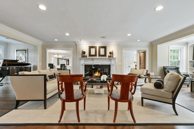living area with recessed lighting, ornamental molding, a glass covered fireplace, and a chandelier