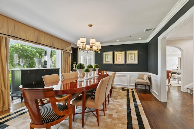 dining area featuring a chandelier, arched walkways, ornamental molding, a wainscoted wall, and recessed lighting