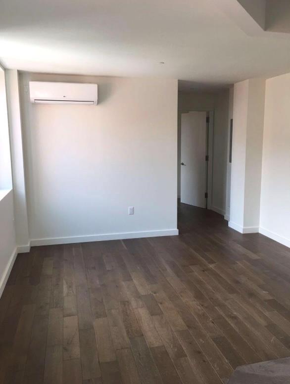 unfurnished room featuring baseboards, a wall mounted AC, and dark wood-style floors