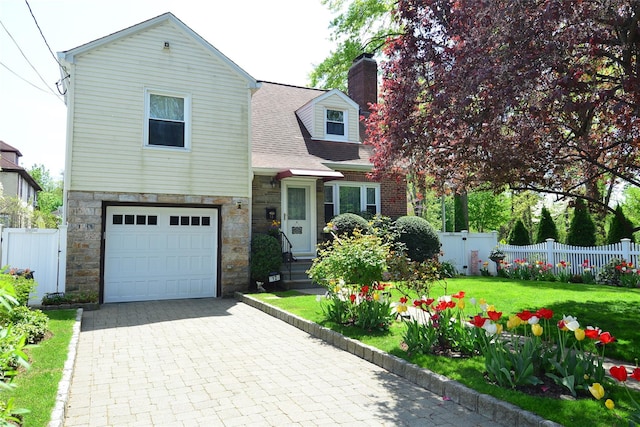 view of front of property with a front yard, decorative driveway, fence, an attached garage, and stone siding