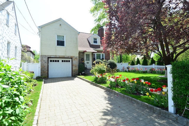 view of front facade with fence, an attached garage, stone siding, a front yard, and a chimney