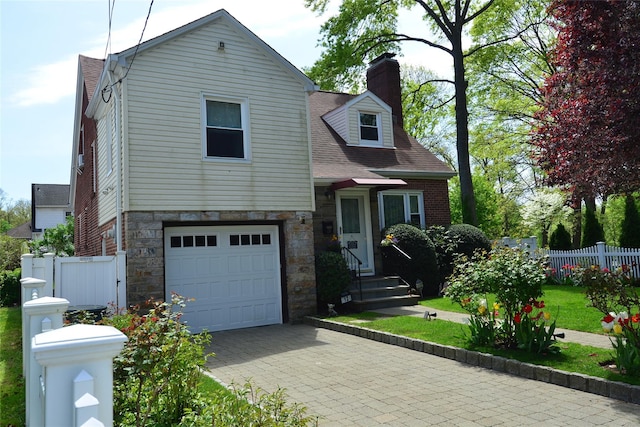 view of front of home with roof with shingles, entry steps, a garage, fence, and stone siding