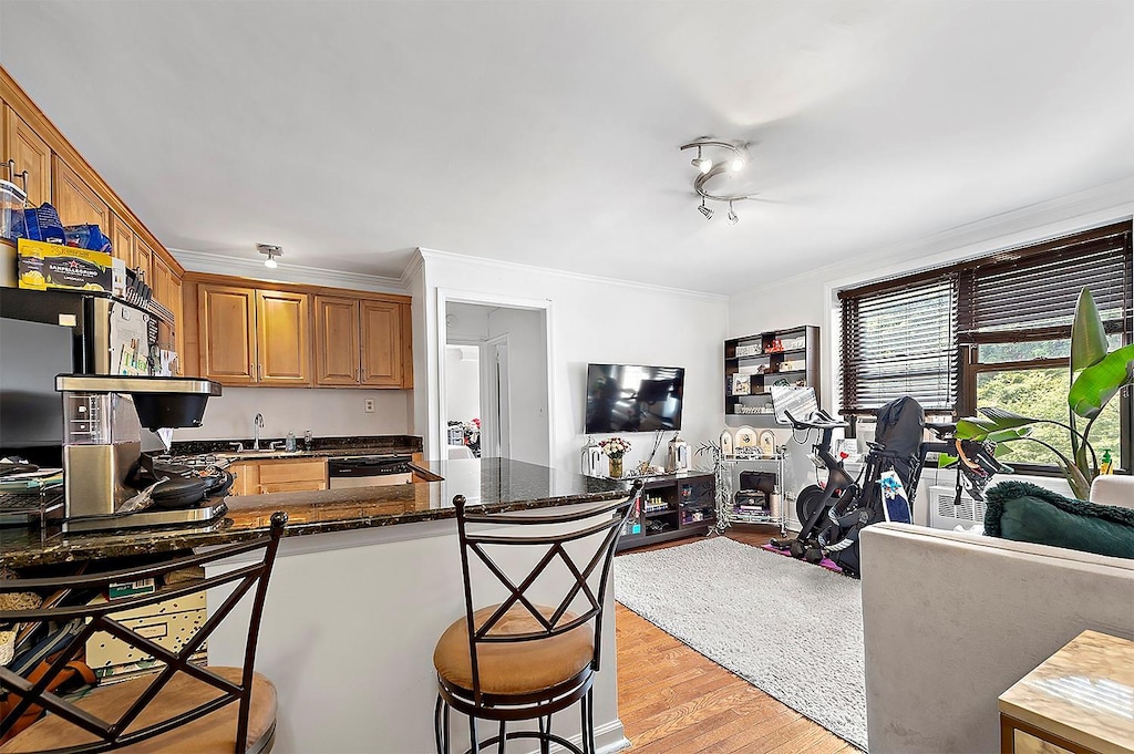 4523 Broadway Ave Unit 7D, New York Manhattan, NY 10040 - kitchen featuring crown molding, open floor plan, light wood finished floors, and a kitchen bar