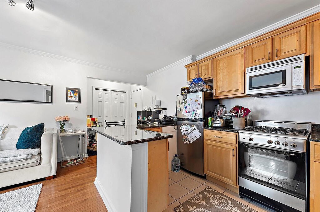 4523 Broadway Ave Unit 7D, New York Manhattan, NY 10040 - kitchen with crown molding, a kitchen island, stainless steel appliances, and dark stone countertops
