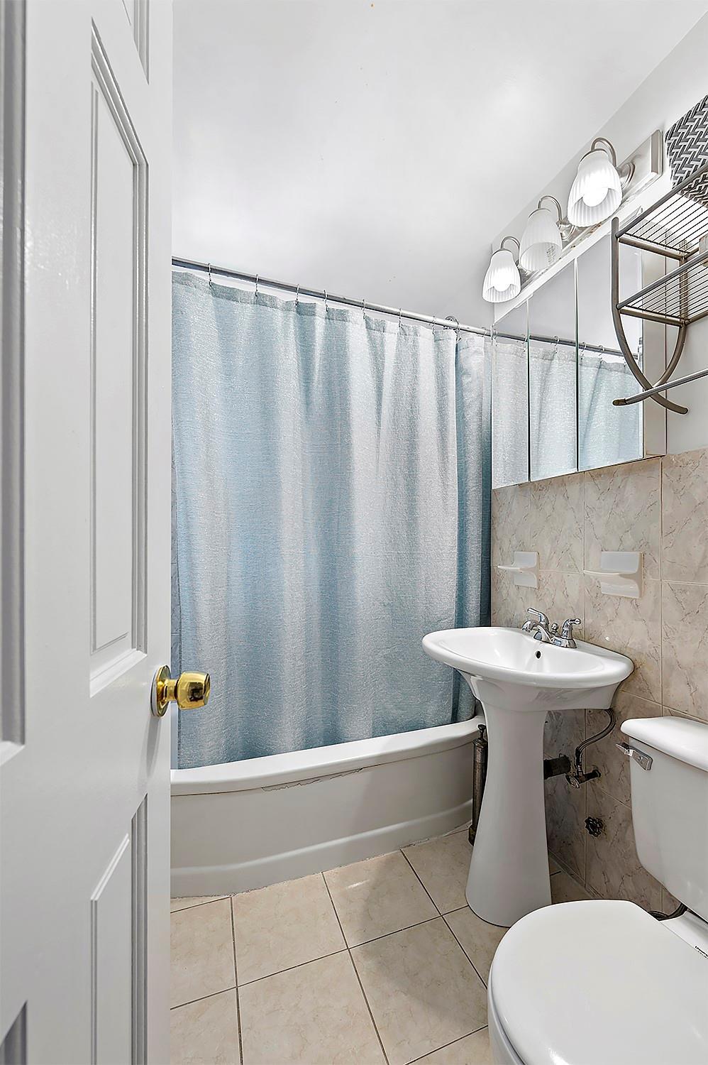 4523 Broadway Ave Unit 7D, New York Manhattan, NY 10040 - bathroom featuring tile patterned floors, toilet, tile walls, and shower / bath combination with curtain