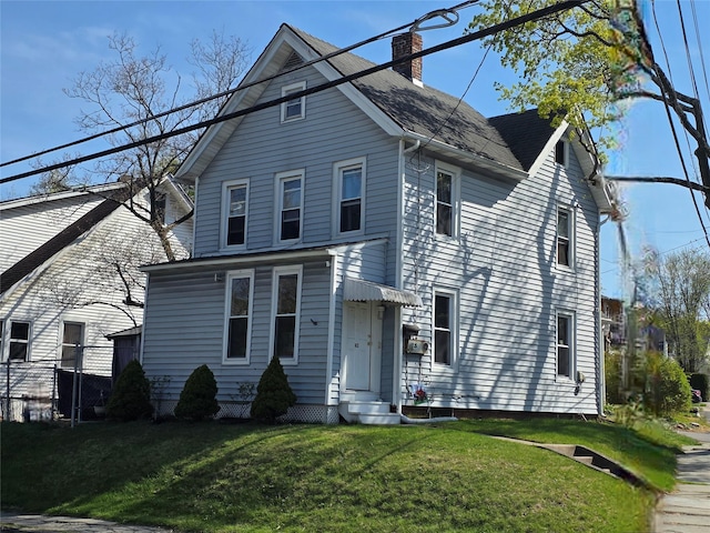 view of front of house with entry steps, a chimney, roof with shingles, and a front yard