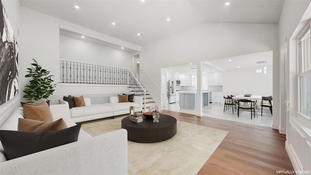 living room with wood finished floors, stairway, high vaulted ceiling, and recessed lighting
