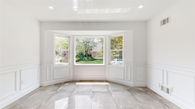 empty room with a decorative wall, wainscoting, and recessed lighting