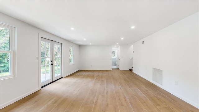 unfurnished living room with light wood-style floors, recessed lighting, healthy amount of natural light, french doors, and baseboards