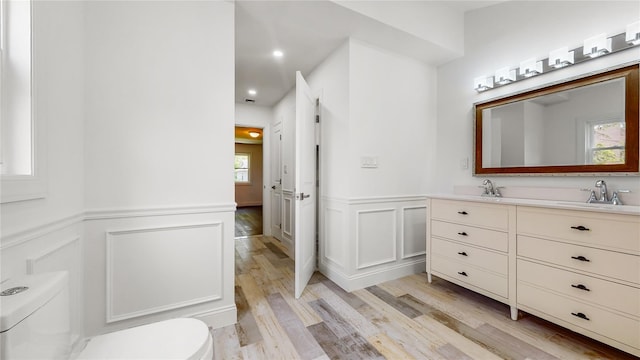 bathroom featuring toilet, wood finished floors, a wainscoted wall, vanity, and recessed lighting