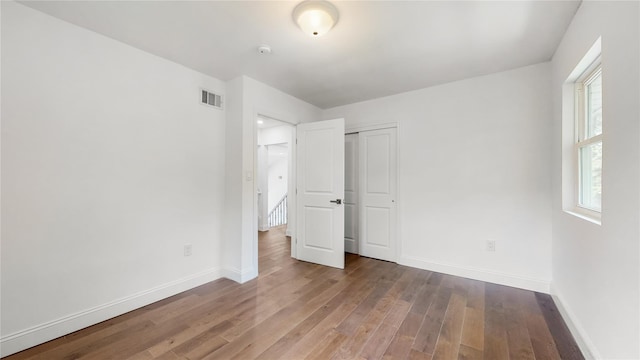 unfurnished bedroom featuring wood finished floors, baseboards, and a closet