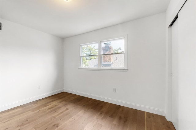 unfurnished bedroom featuring baseboards, light wood-type flooring, and a closet