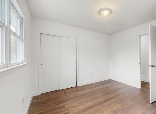 unfurnished bedroom featuring light wood-style flooring, a closet, and baseboards