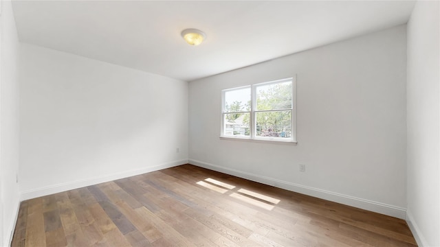 unfurnished room featuring hardwood / wood-style floors and baseboards