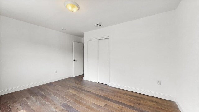 unfurnished bedroom with wood finished floors, baseboards, and a closet