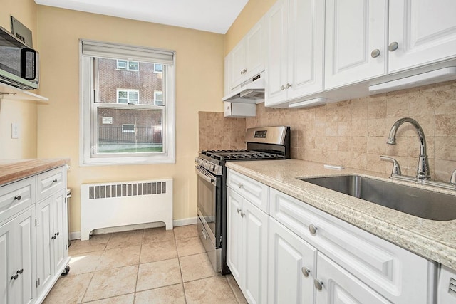 121 N Broadway # 31A, White Plains, NY 10603 - kitchen featuring appliances with stainless steel finishes, radiator, a sink, under cabinet range hood, and tasteful backsplash
