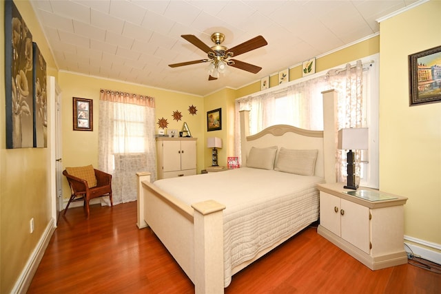 bedroom with baseboards, ornamental molding, a ceiling fan, and wood finished floors