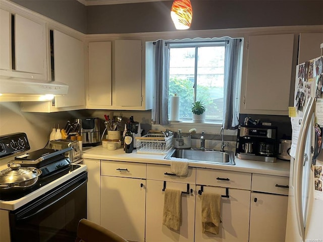 kitchen with a sink, light countertops, freestanding refrigerator, white cabinetry, and black range with electric cooktop