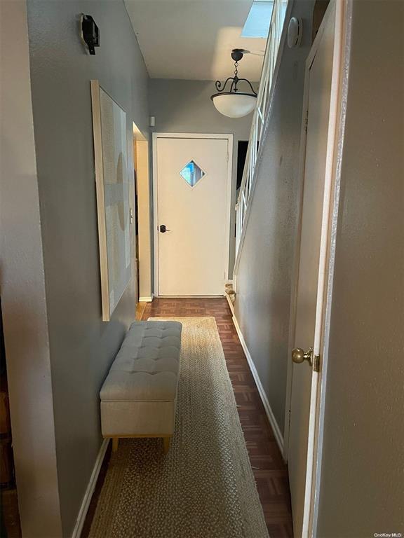hallway with baseboards and dark wood-style floors