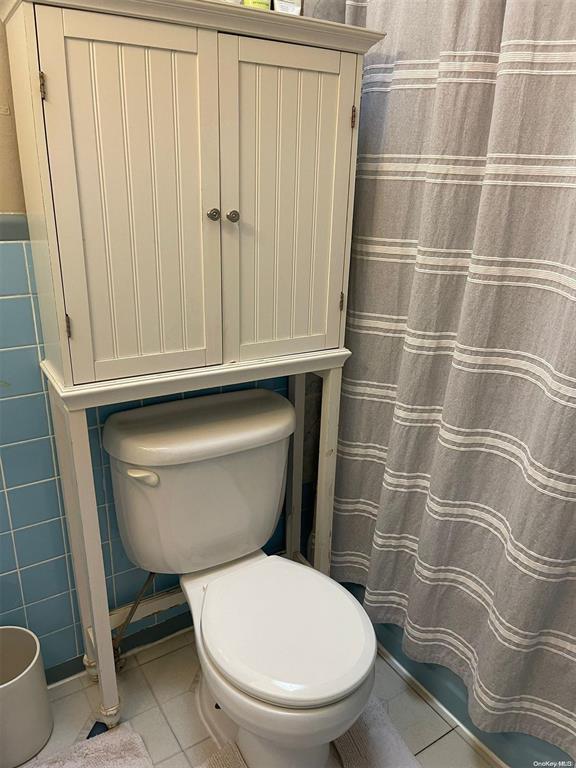 bathroom featuring tile walls, tile patterned flooring, and toilet