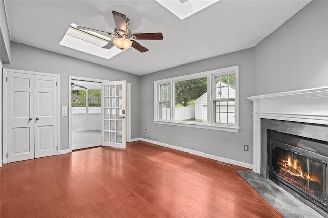 unfurnished living room featuring a skylight, a fireplace with flush hearth, vaulted ceiling, and wood finished floors