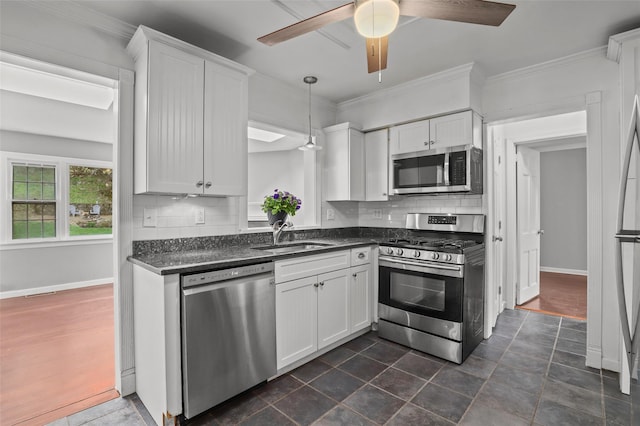 kitchen with stainless steel appliances, a sink, white cabinetry, tasteful backsplash, and ornamental molding