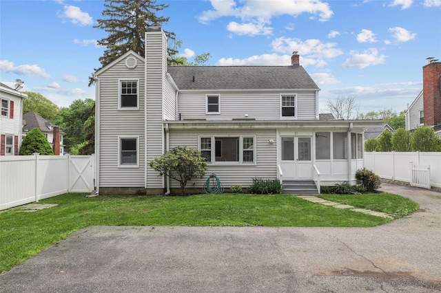 rear view of house featuring a fenced backyard, a chimney, and a lawn