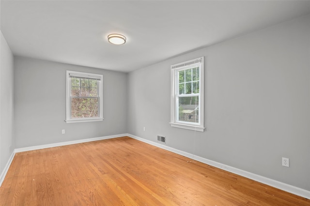 unfurnished room with visible vents, light wood-style flooring, and a healthy amount of sunlight