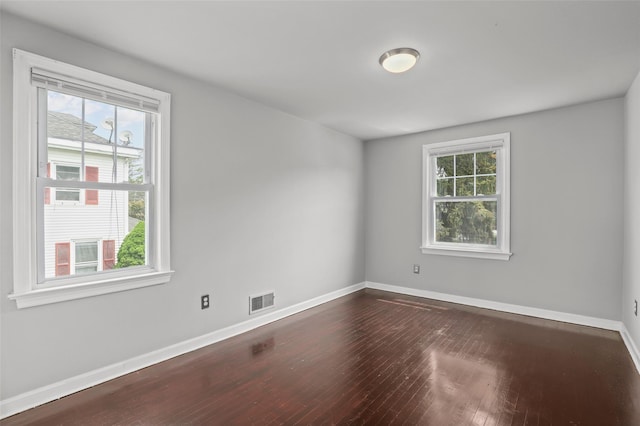 spare room featuring dark wood-style flooring and baseboards
