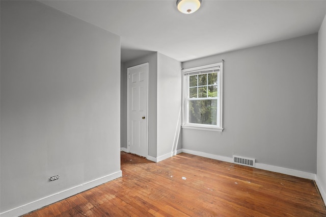 spare room with baseboards and hardwood / wood-style floors