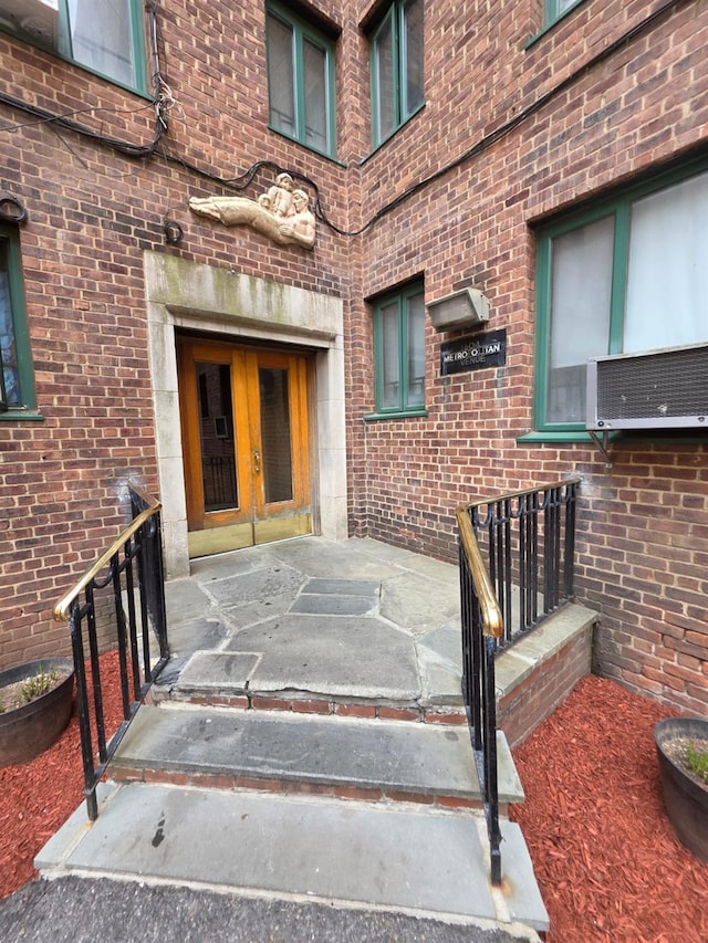 view of exterior entry featuring brick siding and french doors