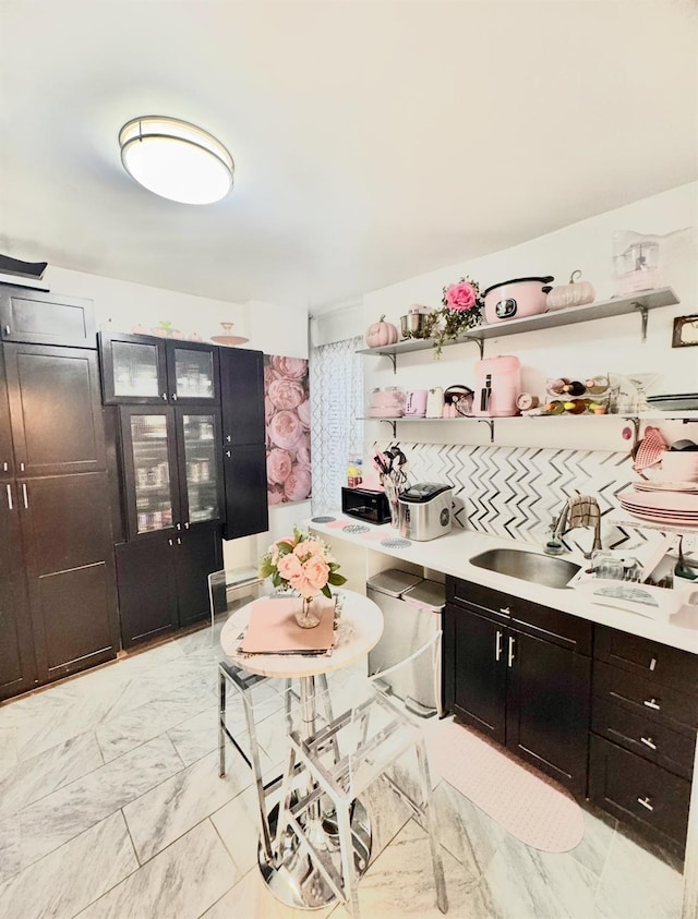 kitchen with open shelves, a sink, marble finish floor, and light countertops