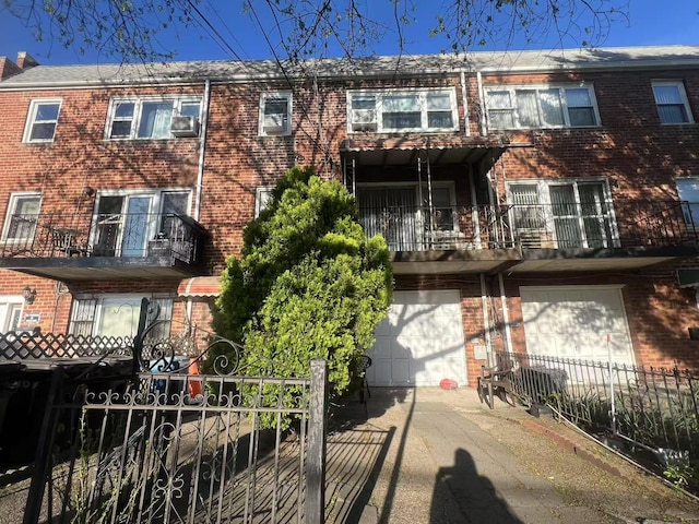 exterior space featuring a balcony, driveway, brick siding, fence, and an attached garage