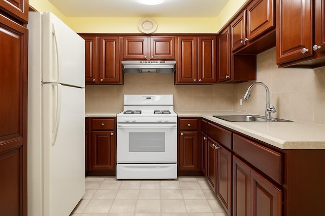 kitchen with a sink, white appliances, backsplash, under cabinet range hood, and light countertops