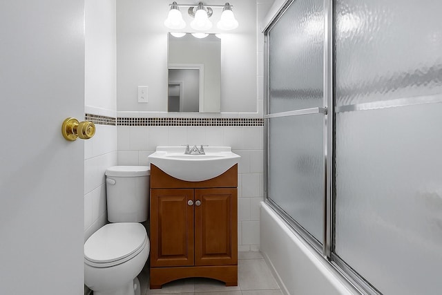 bathroom featuring toilet, shower / bath combination with glass door, tile walls, tile patterned flooring, and vanity