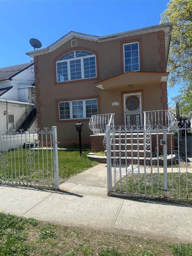 view of front of property featuring a fenced front yard, a porch, stucco siding, and stairway