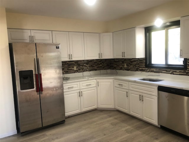 kitchen featuring appliances with stainless steel finishes, light wood-style flooring, backsplash, and white cabinetry